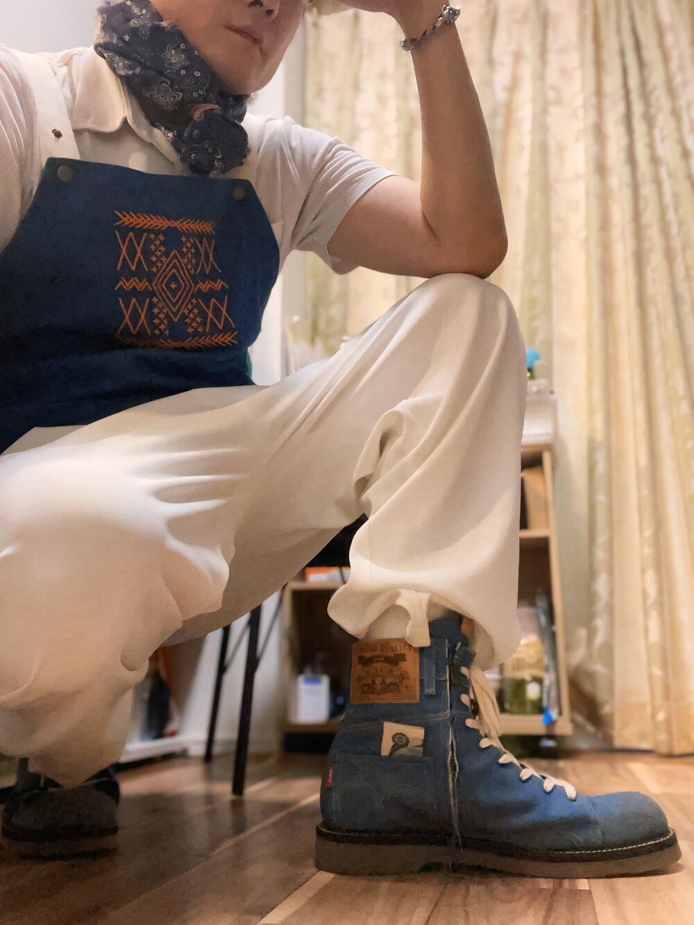 ホワイト系のポロシャツ、ホワイト系のスラックス、ブルー系のブーツを着用したメンズの秋コーディネートの4枚目の写真