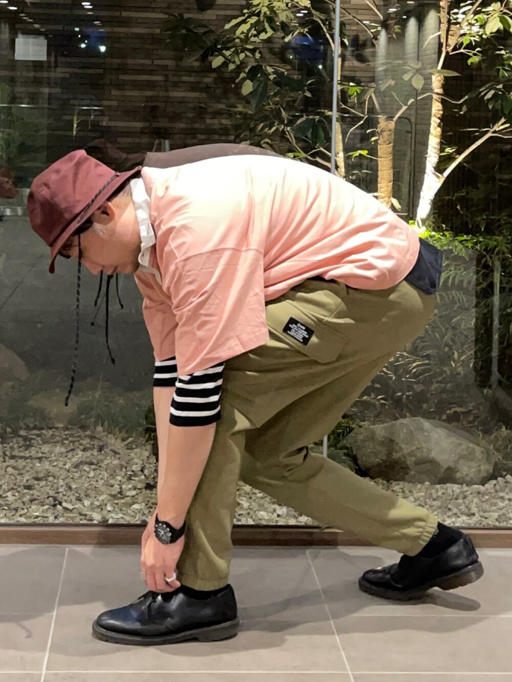 ピンク系のTシャツ/カットソー、ブラック系のTシャツ/カットソー、グリーン系のカーゴパンツを着用したメンズの春コーディネートの4枚目の写真