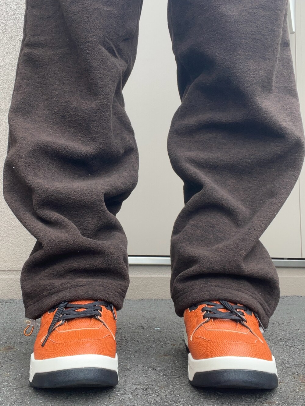 ブラック系のデニムジャケット、ブラウン系のスウェットパンツ、オレンジ系のスニーカーを着用したメンズの秋コーディネートの4枚目の写真