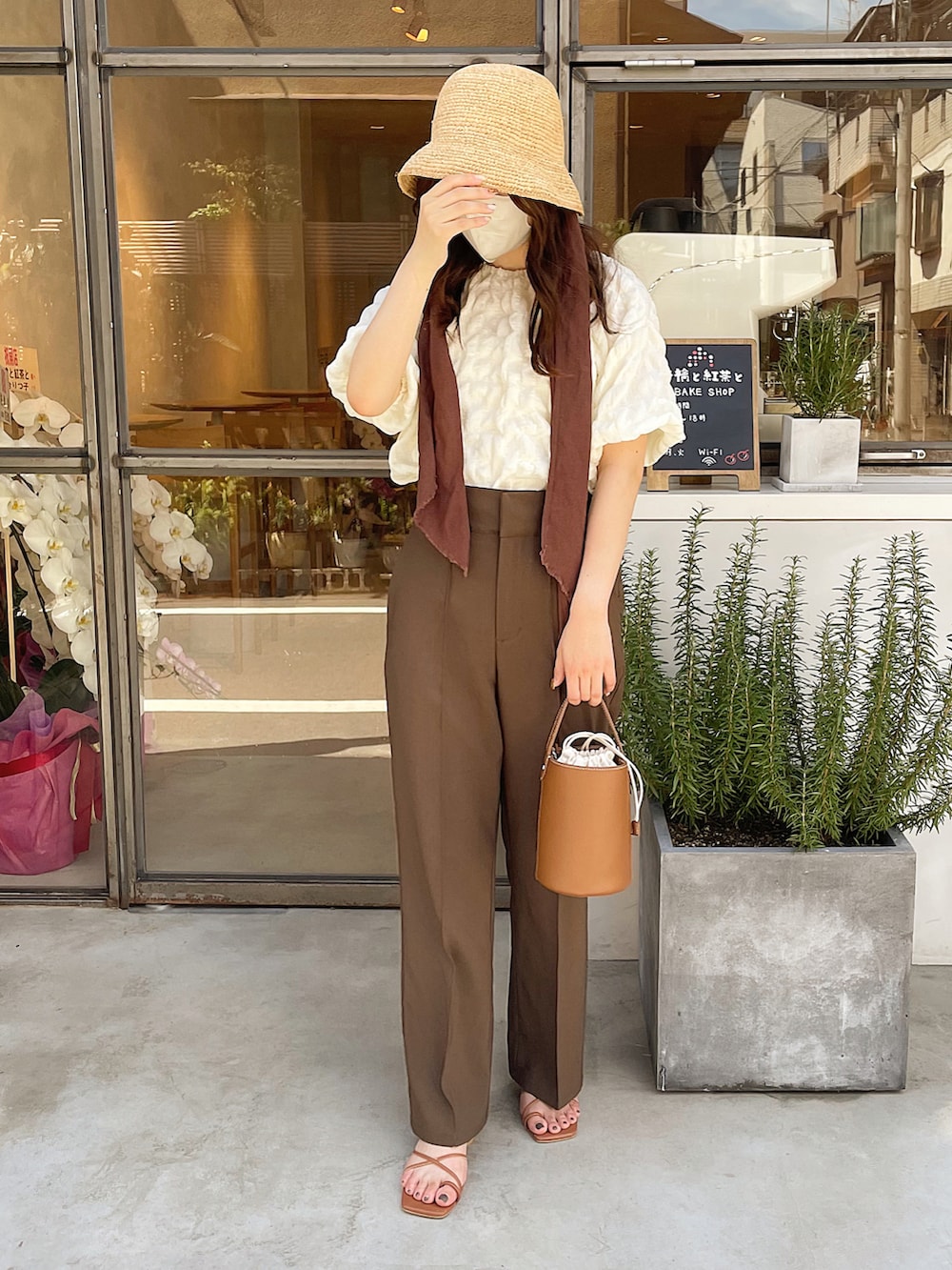 イエロー系のハンドバッグ、ブラウン系のシューズ、ブラウン系のパンツを着用したレディースの夏コーディネートの3枚目の写真