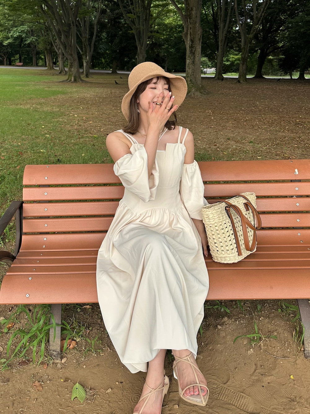 ホワイト系のワンピース、ホワイト系のかごバッグ、ベージュ系のサンダルを着用したレディースの夏コーディネートの3枚目の写真