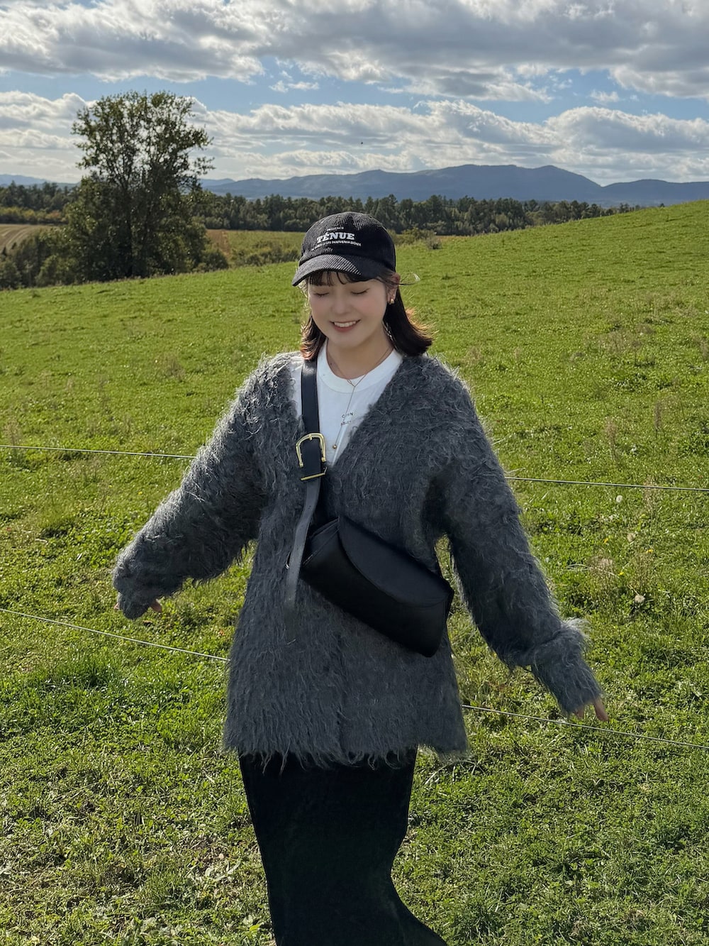 グレー系のカーディガン/ボレロ、ブラック系のスカート、ホワイト系のTシャツ/カットソーを着用したレディースの秋コーディネートの2枚目の写真