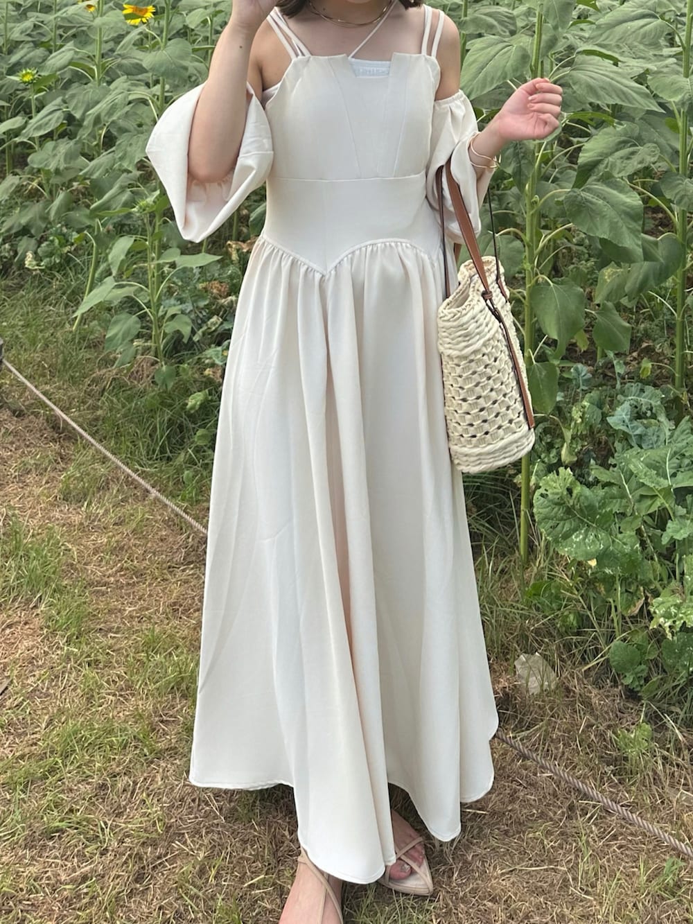 ホワイト系のワンピース、ホワイト系のかごバッグ、ベージュ系のサンダルを着用したレディースの夏コーディネートの2枚目の写真