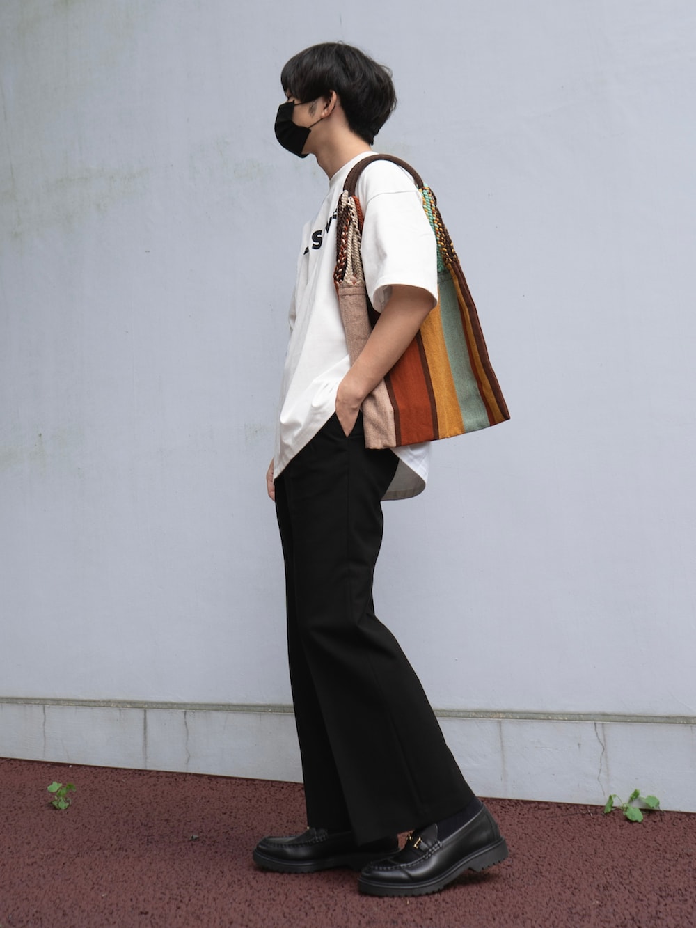 ホワイト系のトップス、ブラック系のスラックス、レッド系のバッグを着用したメンズの秋コーディネートの2枚目の写真