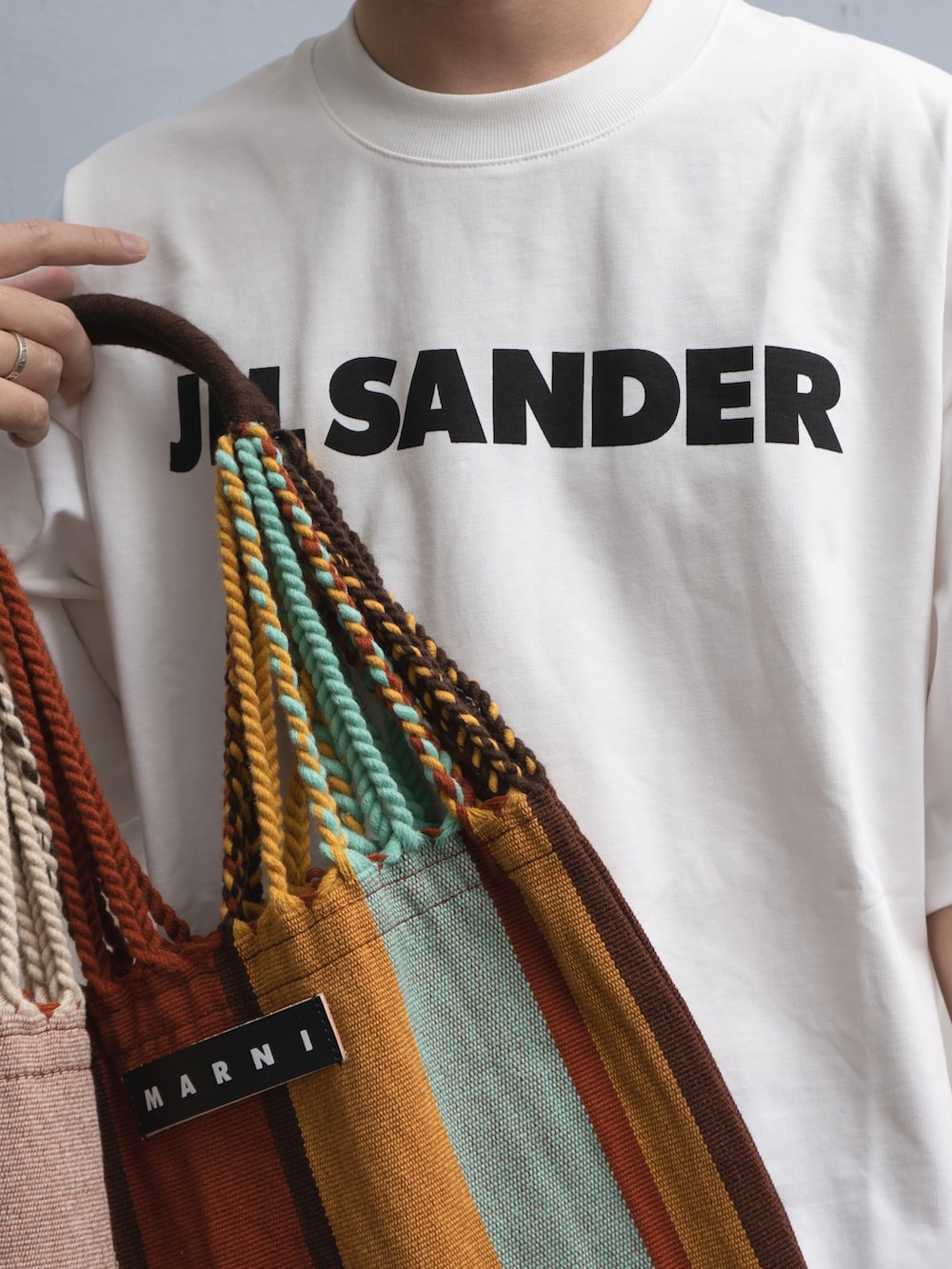 ホワイト系のトップス、ブラック系のスラックス、レッド系のバッグを着用したメンズの秋コーディネートの4枚目の写真