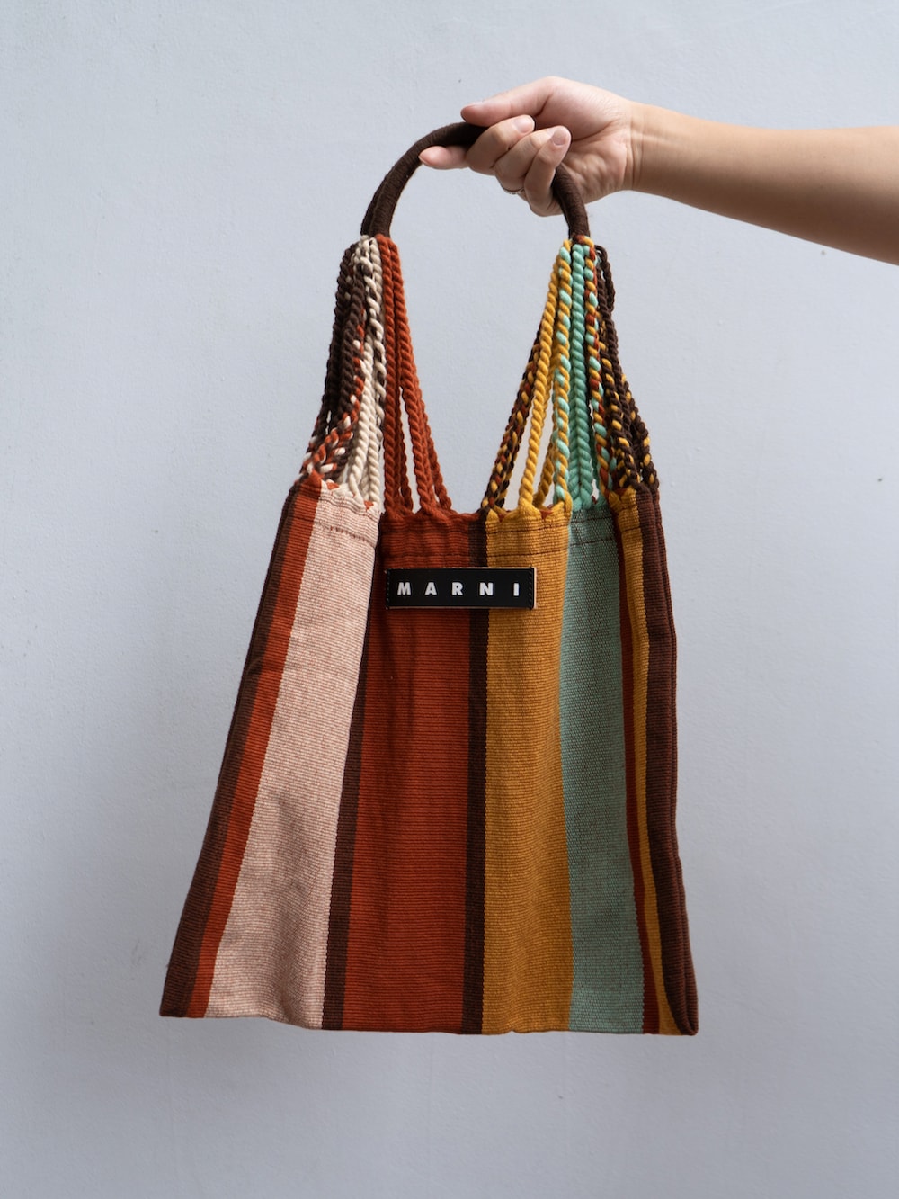 ホワイト系のトップス、ブラック系のスラックス、レッド系のバッグを着用したメンズの秋コーディネートの3枚目の写真