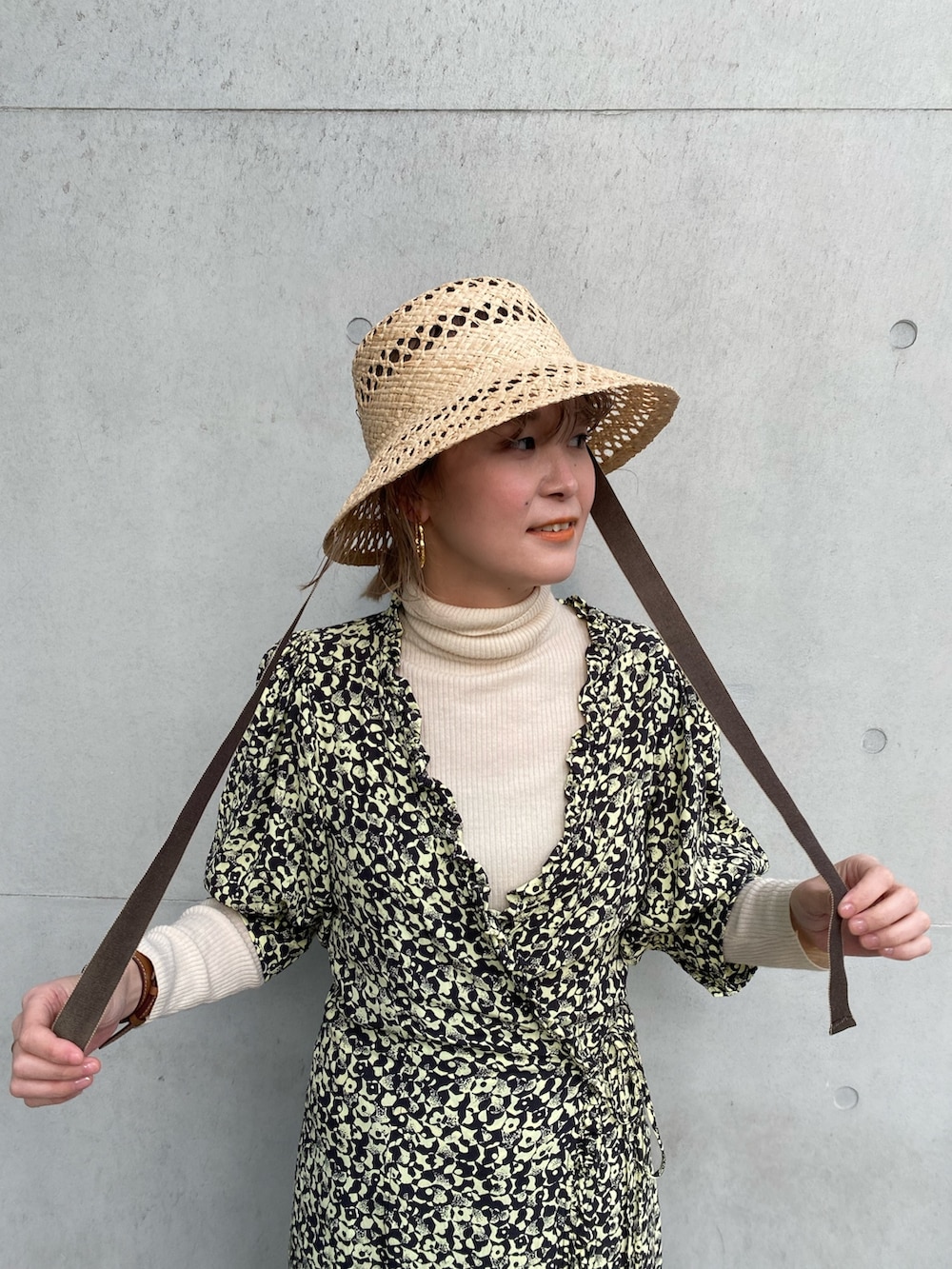 ブラック系のスニーカー、イエロー系のワンピース、ベージュ系のハットを着用したレディースの春コーディネートの3枚目の写真