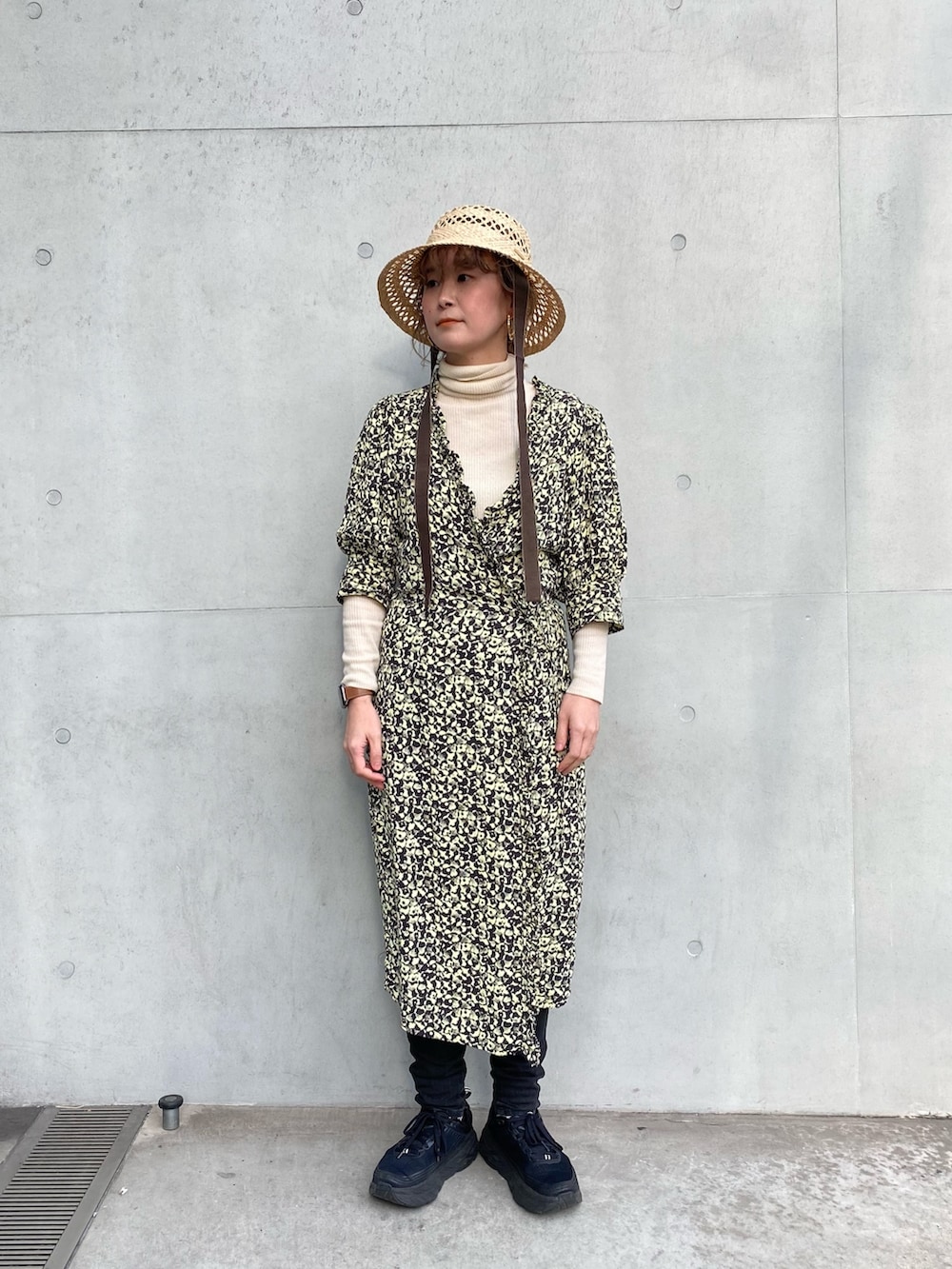 ブラック系のスニーカー、イエロー系のワンピース、ベージュ系のハットを着用したレディースの春コーディネートの2枚目の写真