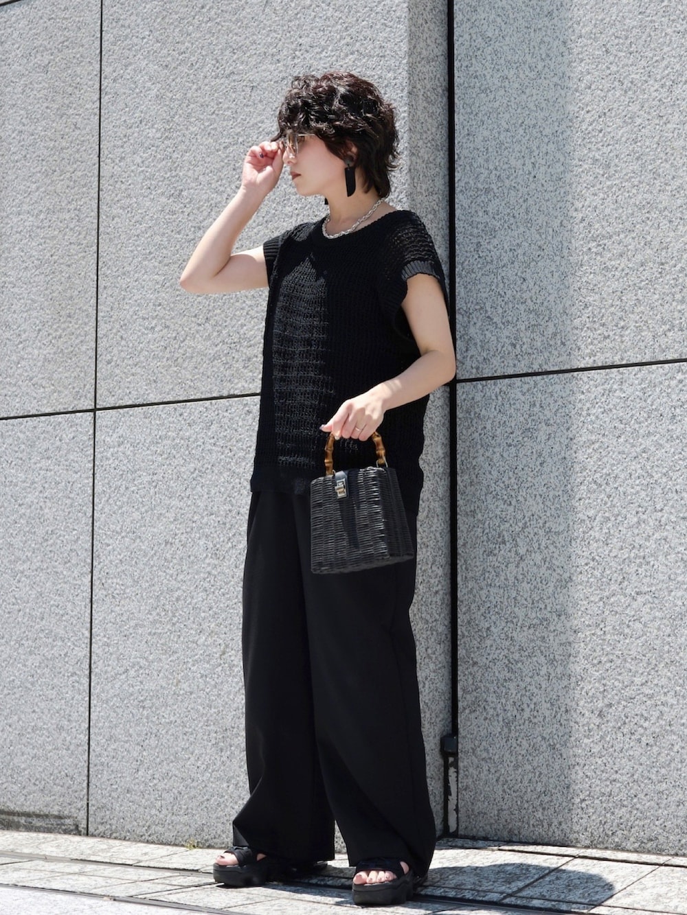 ブラック系のサンダル、ブラック系のスラックス、ブラック系のバッグを着用したレディースの夏コーディネートの2枚目の写真
