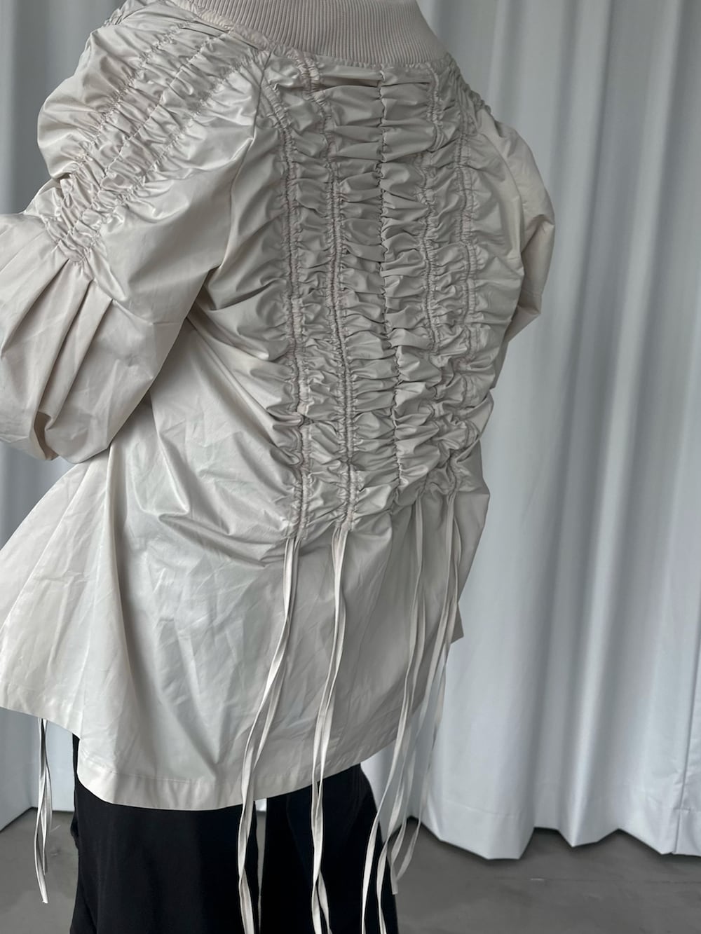 ブラック系のスウェットパンツ、ブラック系のタンクトップ、ホワイト系のブルゾンを着用したレディースの秋コーディネートの5枚目の写真