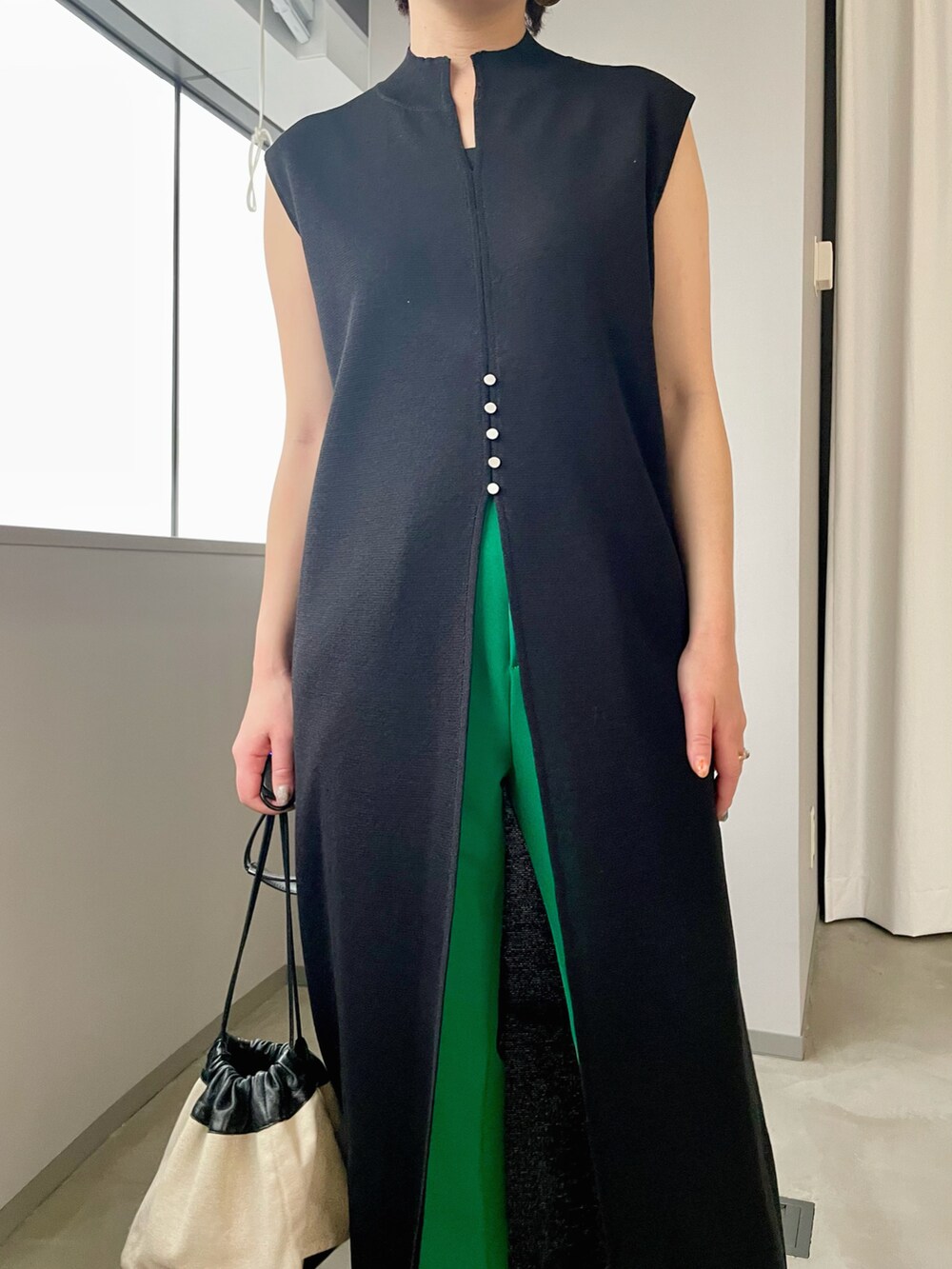 ホワイト系のショルダーバッグ、ブラック系のニット/セーター、グリーン系のスラックスを着用したレディースの春コーディネートの3枚目の写真