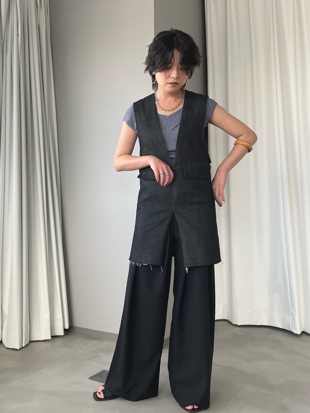 ブラック系のベスト、ブラック系のスラックス、ブルー系のニット/セーターを着用したレディースの夏コーディネートの2枚目の写真