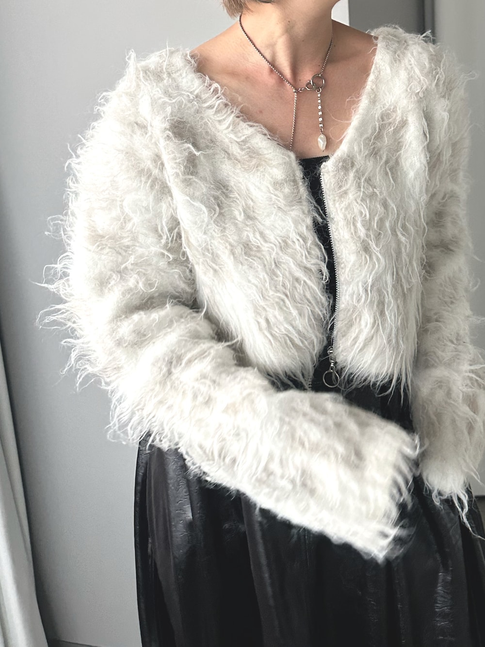 ホワイト系のニット/セーター、ブラック系のスカート、シルバー系のブーツを着用したレディースの秋コーディネートの2枚目の写真