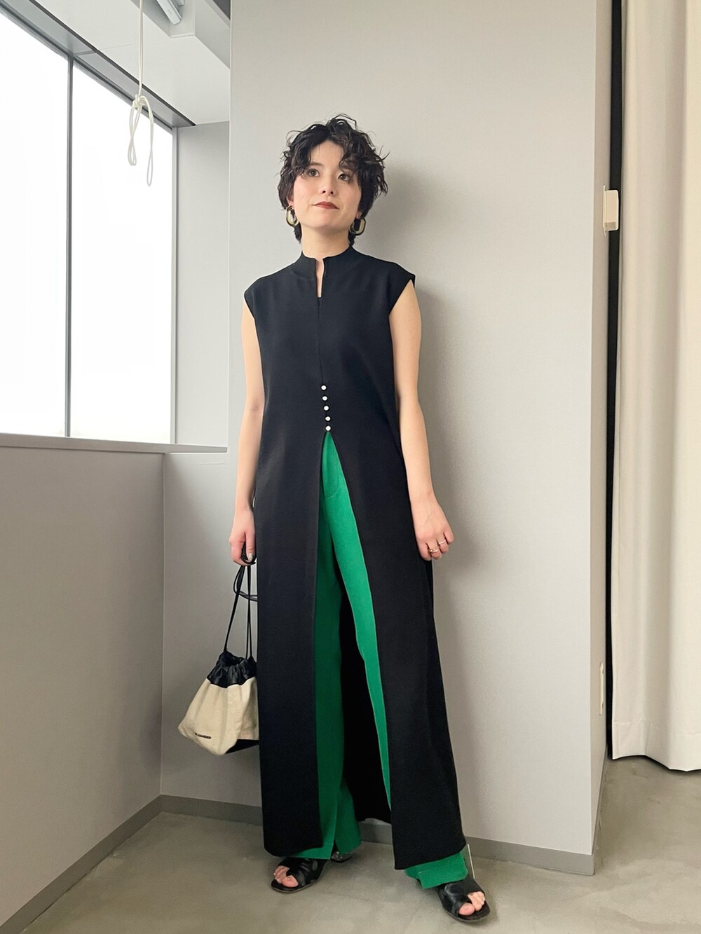 ホワイト系のショルダーバッグ、ブラック系のニット/セーター、グリーン系のスラックスを着用したレディースの春コーディネートの2枚目の写真