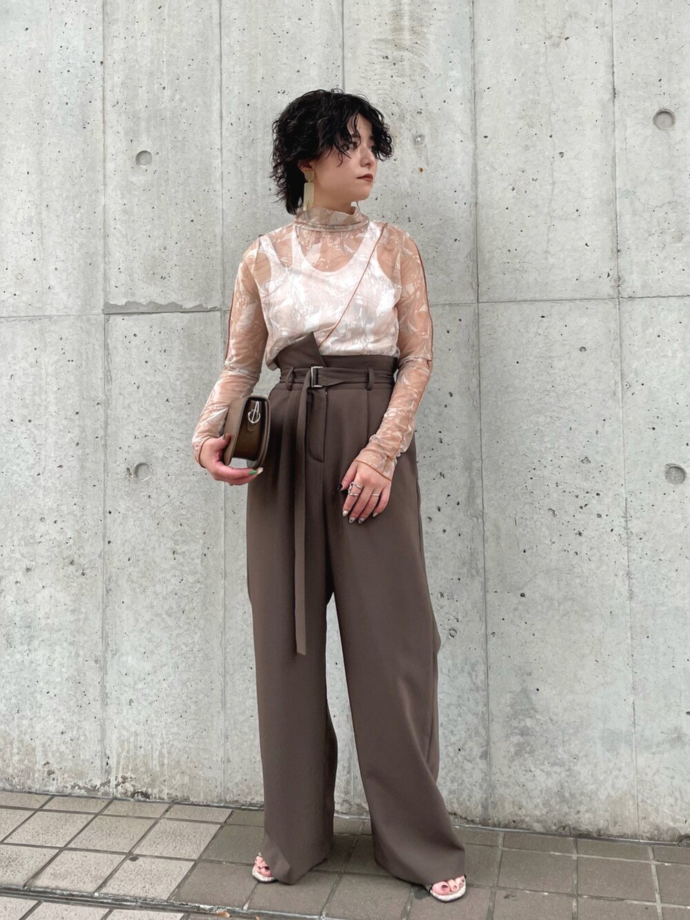 ブラウン系のスラックス、ブラウン系のTシャツ/カットソー、ホワイト系のタンクトップを着用したレディースの春コーディネートの2枚目の写真