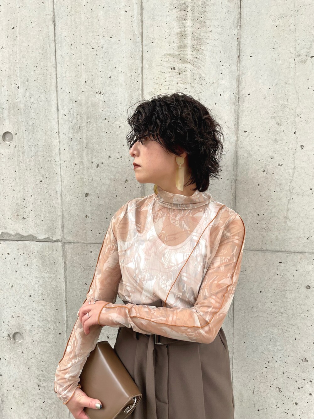 ブラウン系のスラックス、ブラウン系のTシャツ/カットソー、ホワイト系のタンクトップを着用したレディースの春コーディネートの3枚目の写真