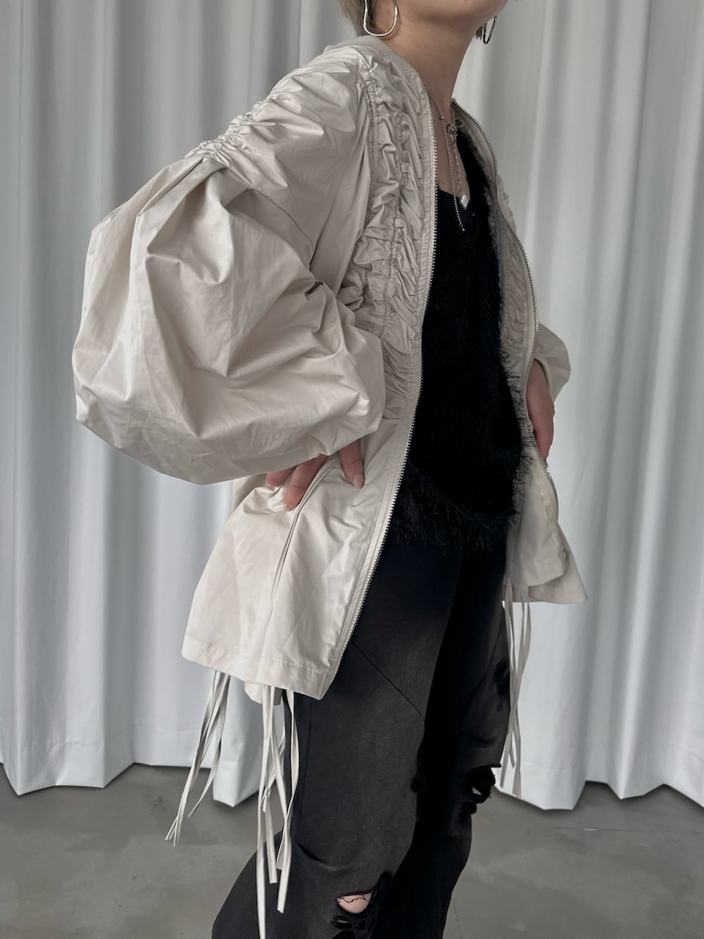 ブラック系のスウェットパンツ、ブラック系のタンクトップ、ホワイト系のブルゾンを着用したレディースの秋コーディネートの4枚目の写真