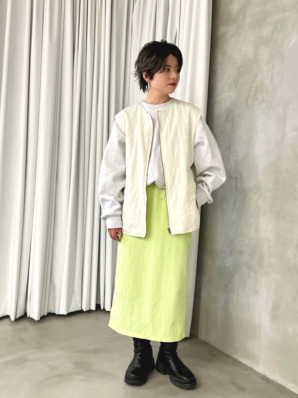 グリーン系のスカート、ホワイト系のスウェット、ホワイト系のベストを着用したレディースの春コーディネートの2枚目の写真