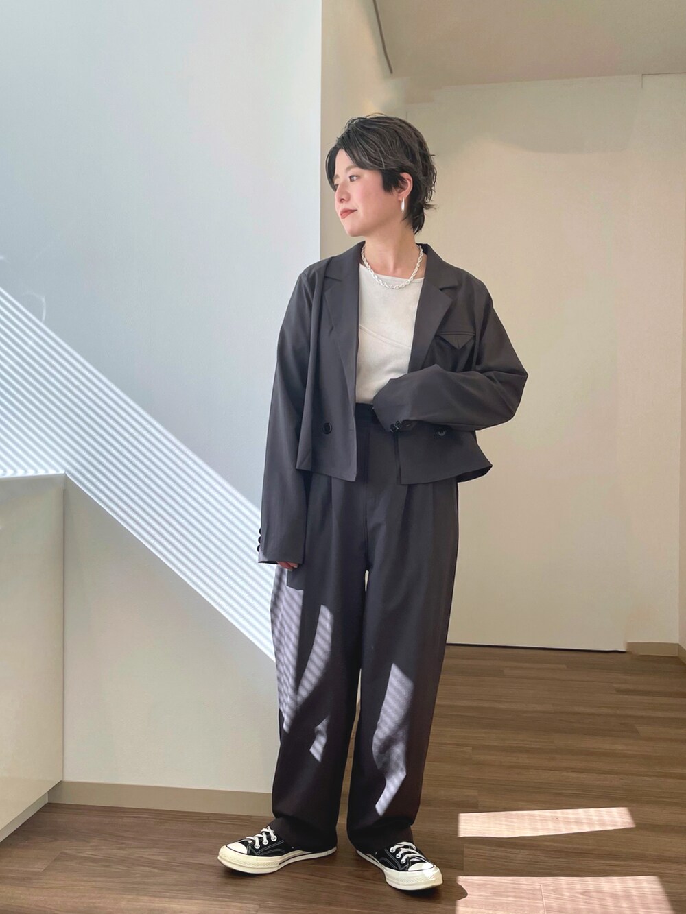 ブラック系のスニーカー、グレー系のテーラードジャケット、ホワイト系のTシャツ/カットソーを着用したレディースの春コーディネートの2枚目の写真