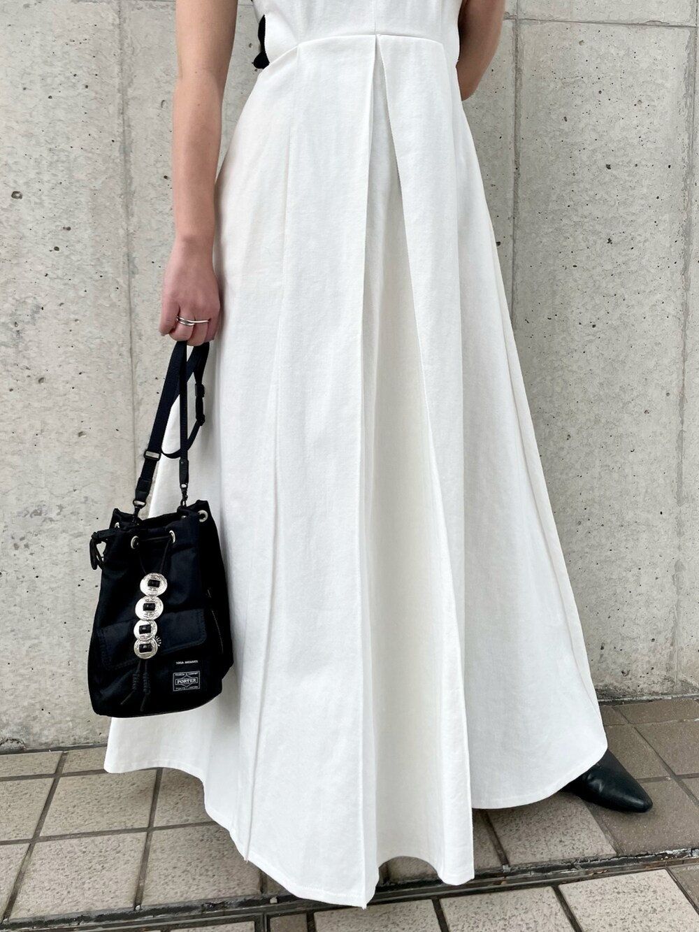 ホワイト系のワンピース、ブラック系のショルダーバッグ、ブラック系のニット/セーターを着用したレディースの春コーディネートの4枚目の写真