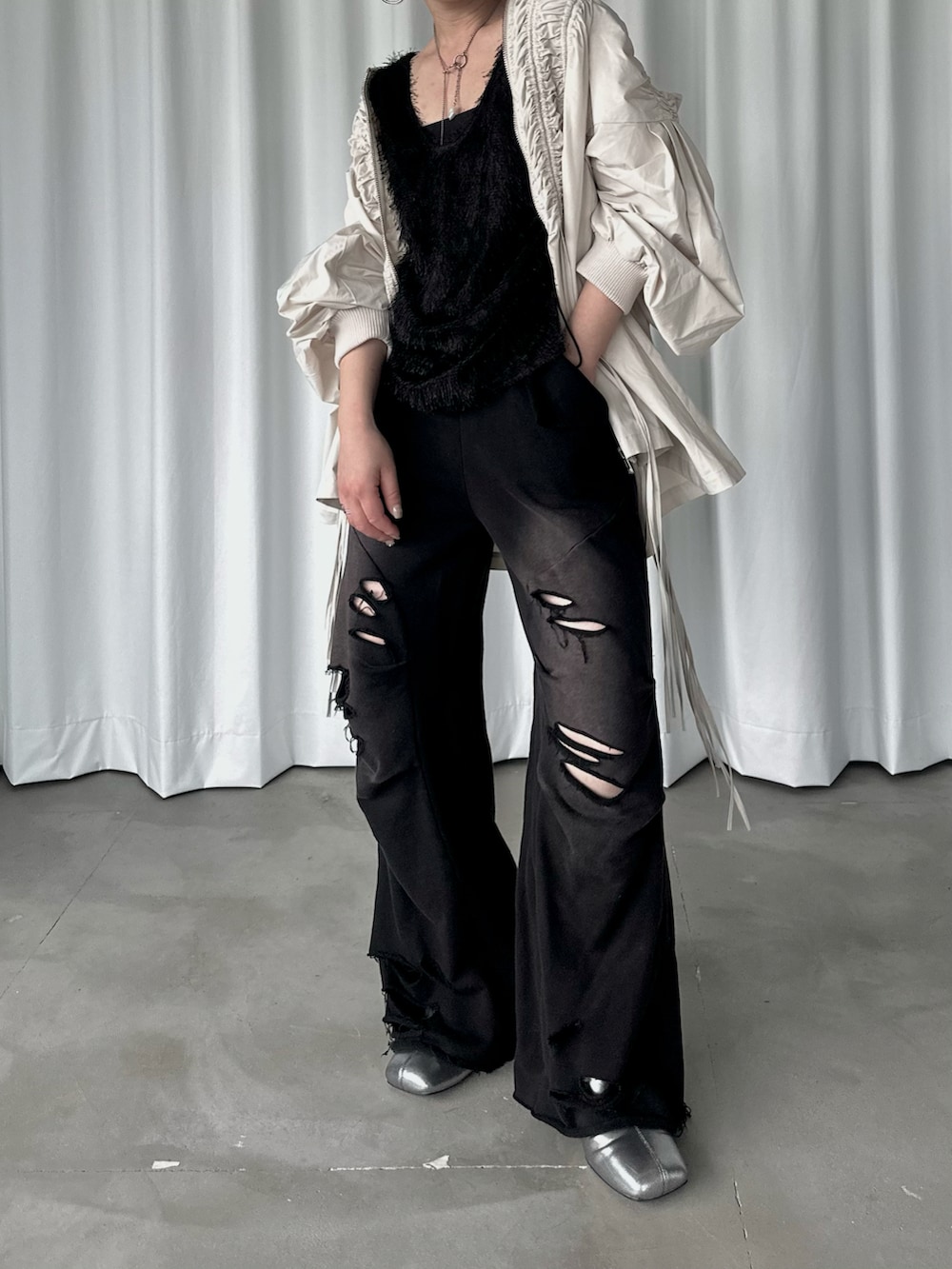 ブラック系のスウェットパンツ、ブラック系のタンクトップ、ホワイト系のブルゾンを着用したレディースの秋コーディネートの2枚目の写真