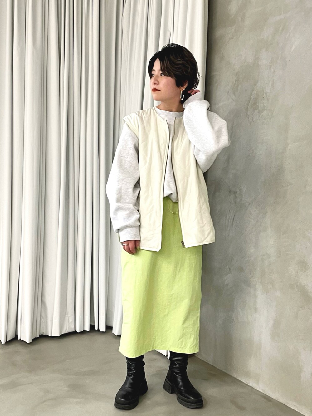 グリーン系のスカート、ホワイト系のスウェット、ホワイト系のベストを着用したレディースの春コーディネートの3枚目の写真
