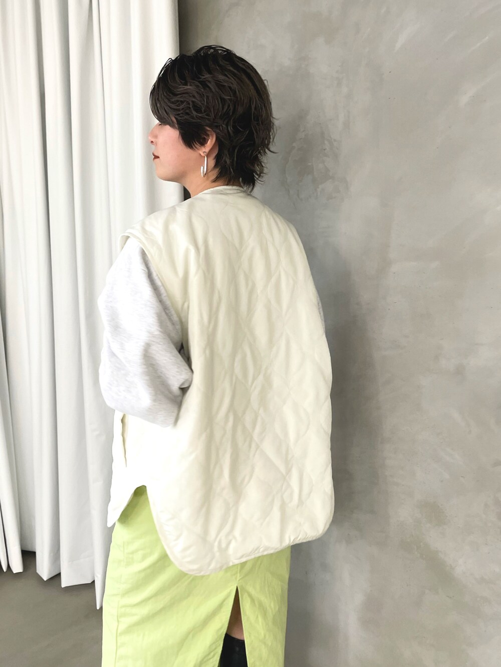 グリーン系のスカート、ホワイト系のスウェット、ホワイト系のベストを着用したレディースの春コーディネートの4枚目の写真