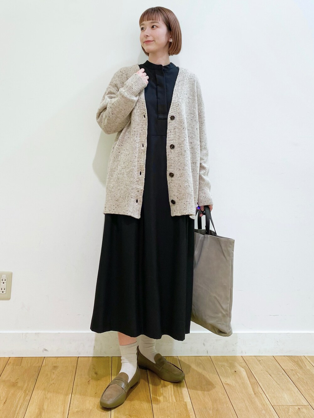 ベージュ系のカーディガン/ボレロ、ブラック系のワンピース、ブラウン系のトートバッグを着用したレディースの冬コーディネートの2枚目の写真