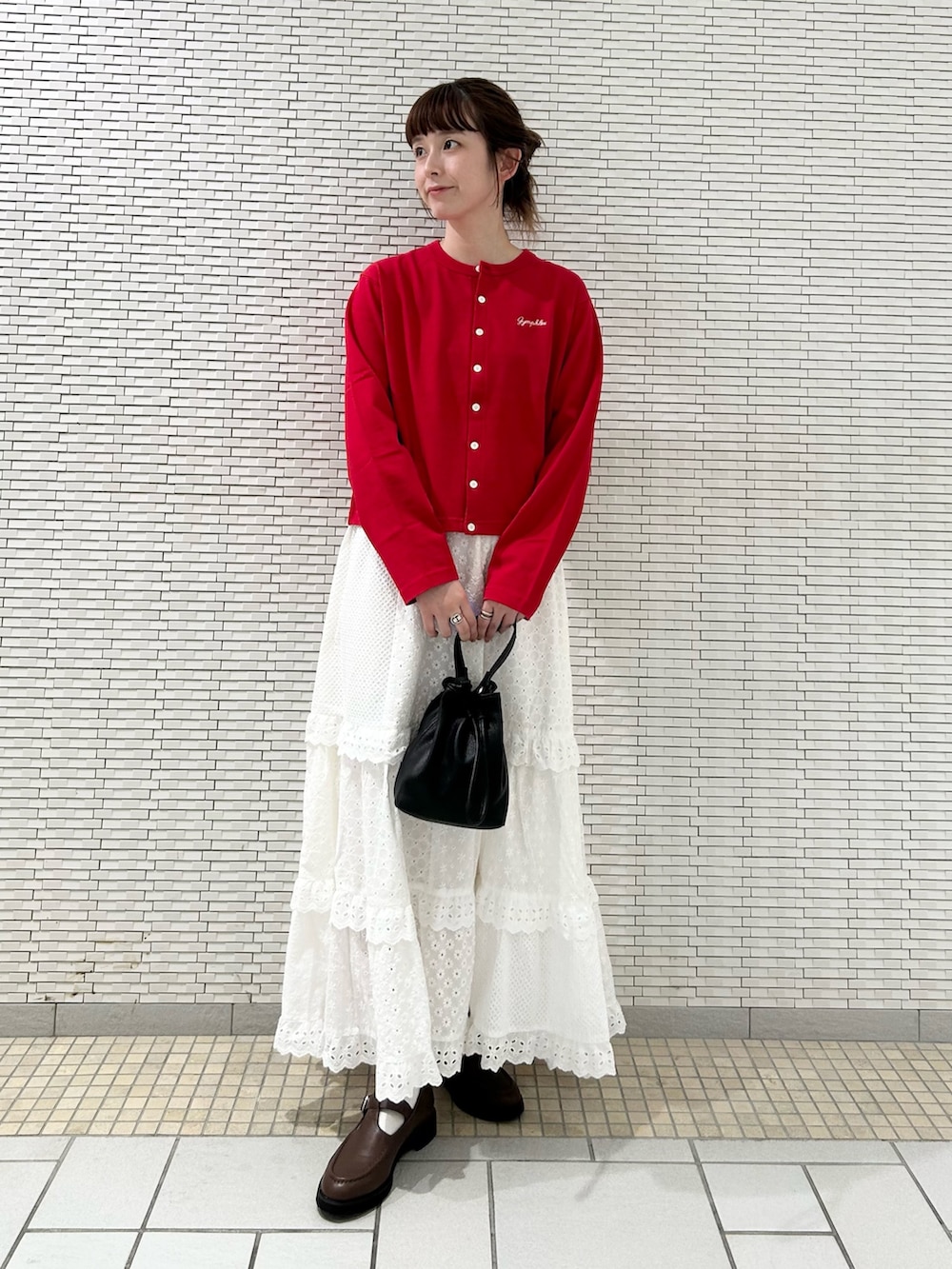 レッド系のカーディガン/ボレロ、ホワイト系のスカート、ブラック系のショルダーバッグを着用したレディースの秋コーディネートの3枚目の写真
