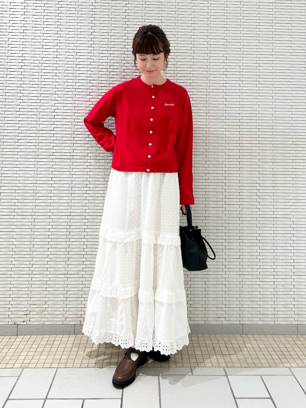 レッド系のカーディガン/ボレロ、ホワイト系のスカート、ブラック系のショルダーバッグを着用したレディースの秋コーディネートの2枚目の写真