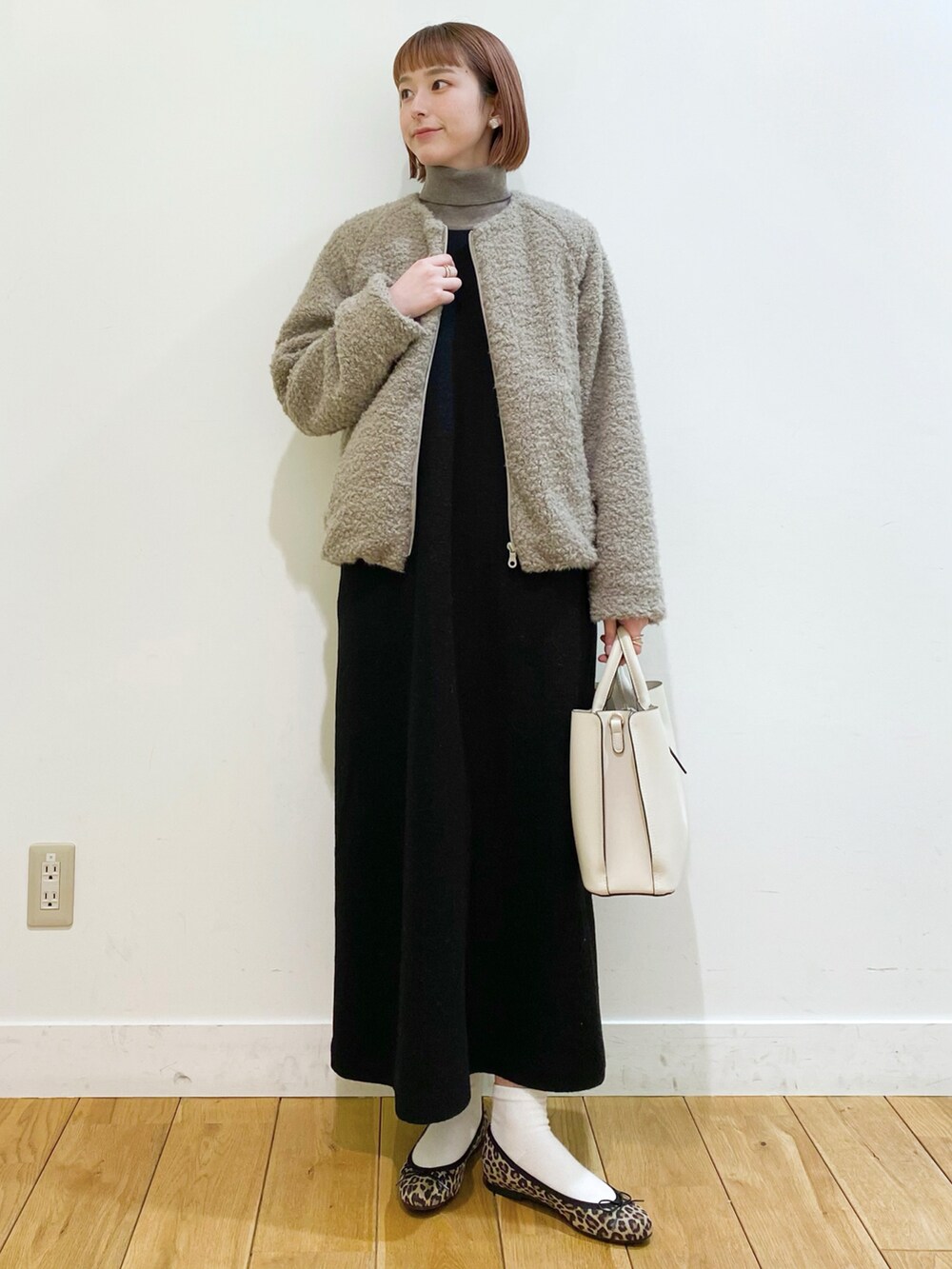 ベージュ系のブルゾン、ブラック系のワンピース、グレー系のニット/セーターを着用したレディースの冬コーディネートの2枚目の写真