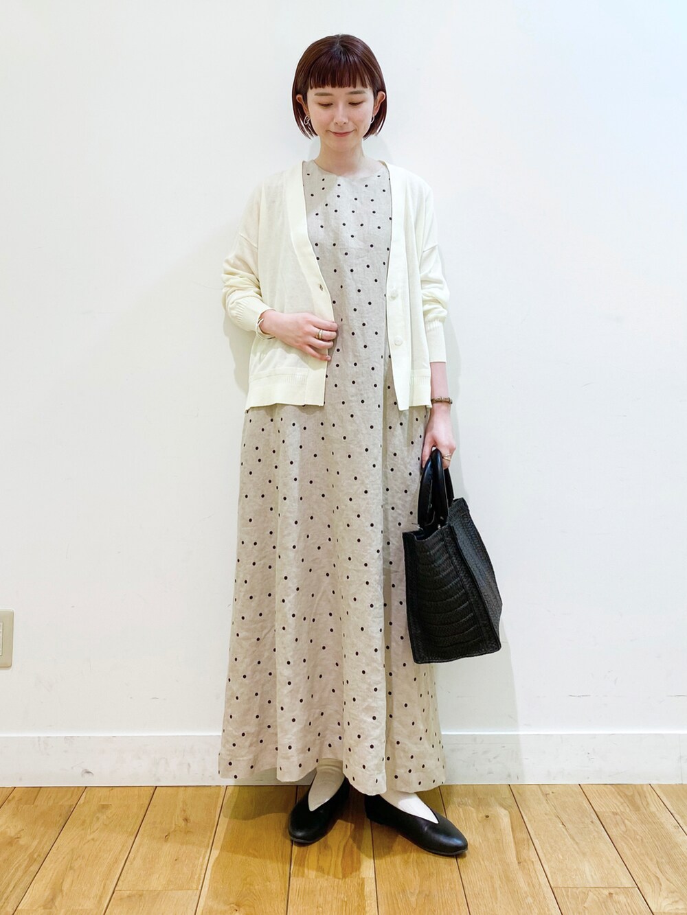 ホワイト系のカーディガン/ボレロ、ベージュ系のワンピース、ブラック系のパンプスを着用したレディースの春コーディネートの2枚目の写真