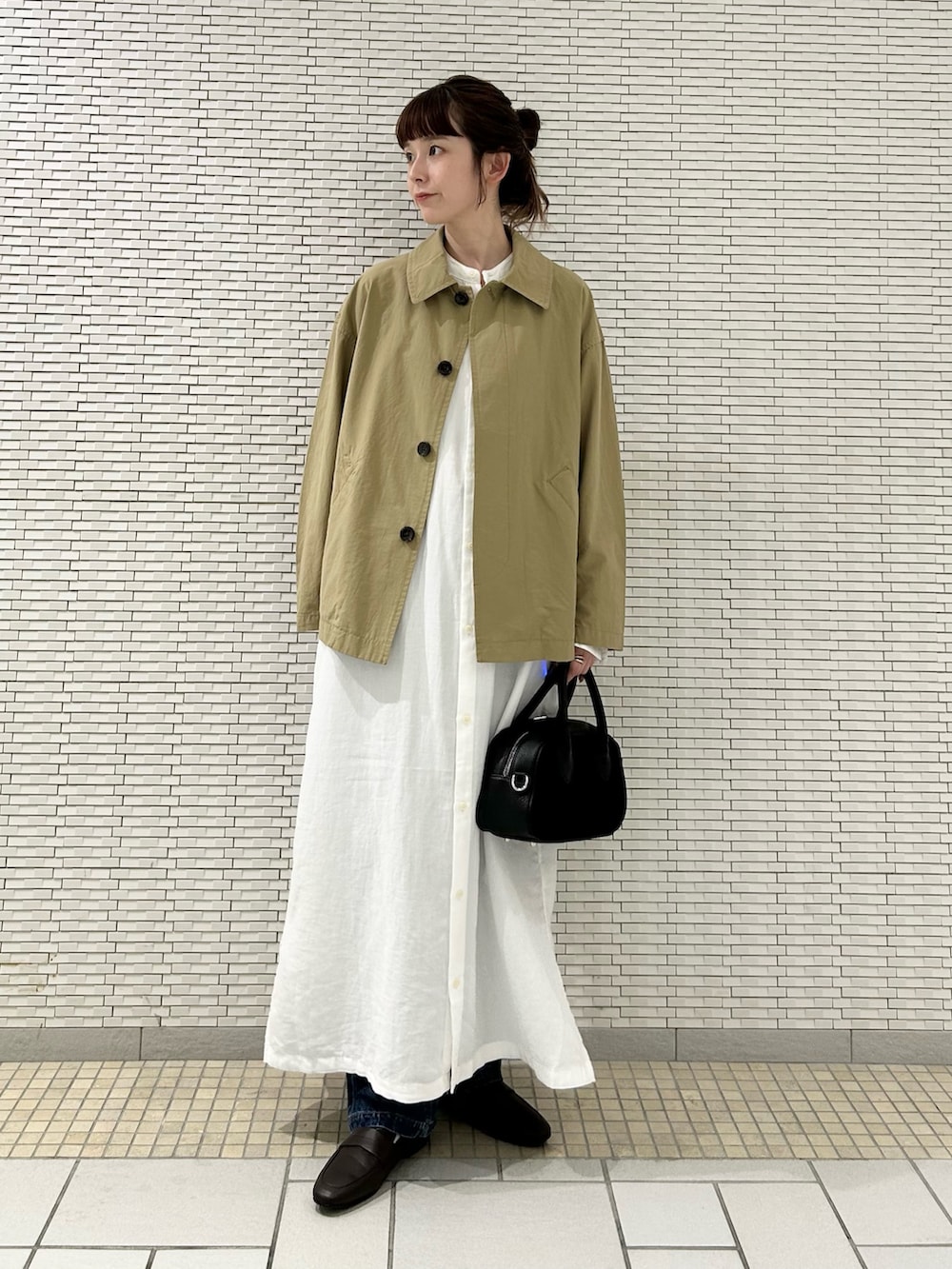 ホワイト系のワンピース、ベージュ系のステンカラーコート、ブルー系のデニムパンツを着用したレディースの秋コーディネートの3枚目の写真