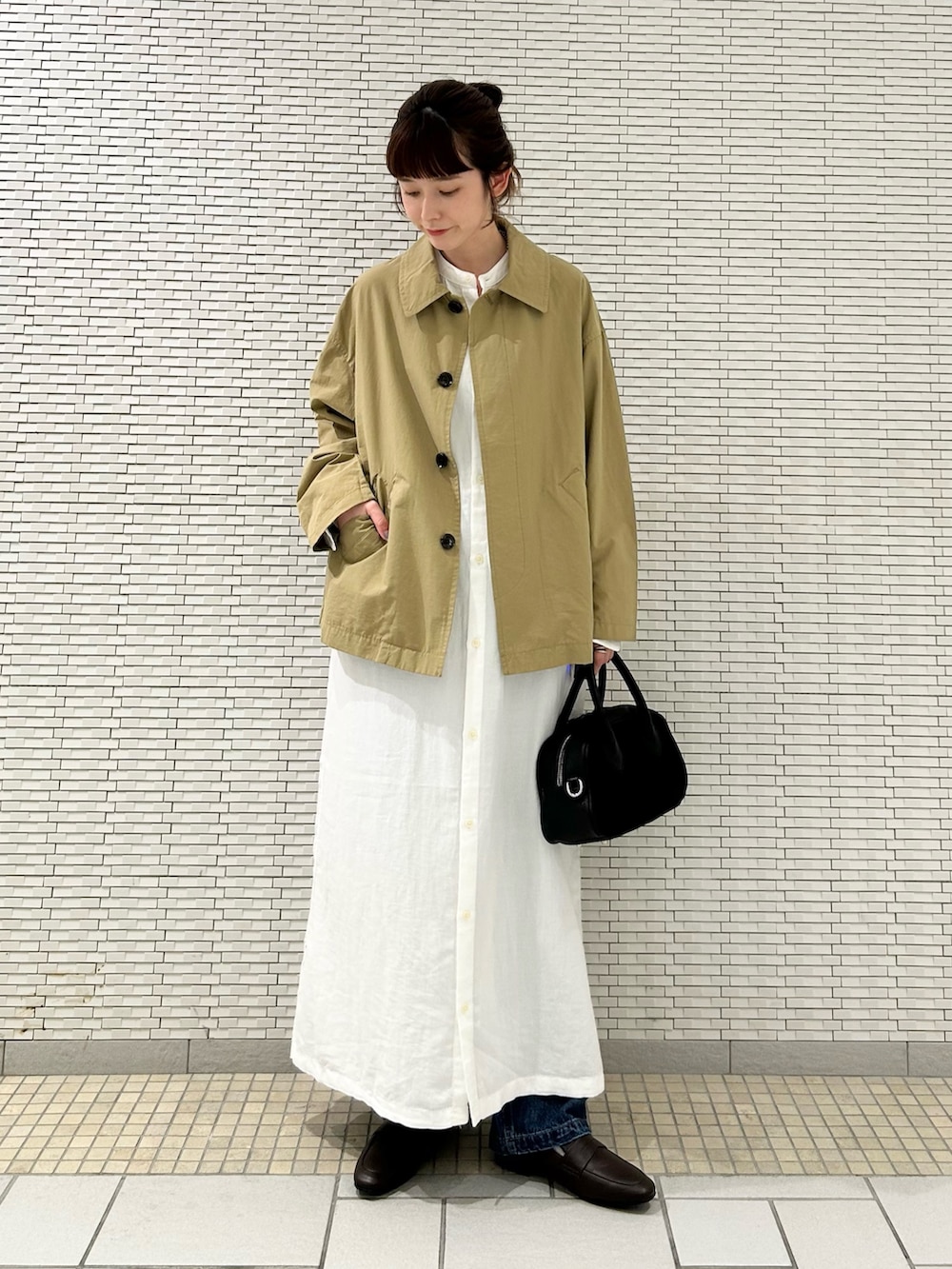 ホワイト系のワンピース、ベージュ系のステンカラーコート、ブルー系のデニムパンツを着用したレディースの秋コーディネートの4枚目の写真