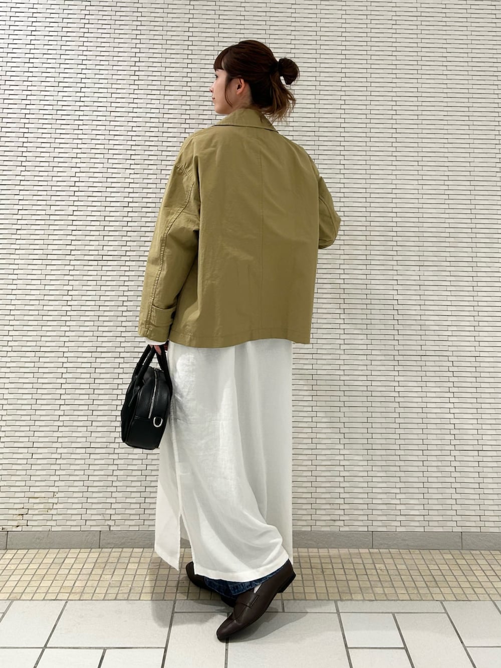 ホワイト系のワンピース、ベージュ系のステンカラーコート、ブルー系のデニムパンツを着用したレディースの秋コーディネートの5枚目の写真