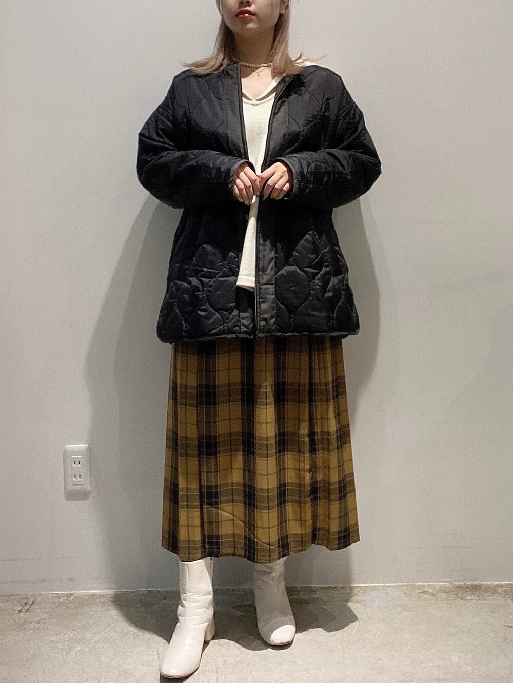 ブラック系のジャケット/アウター、ホワイト系のニット/セーター、イエロー系のスカートを着用したレディースの秋コーディネートの2枚目の写真