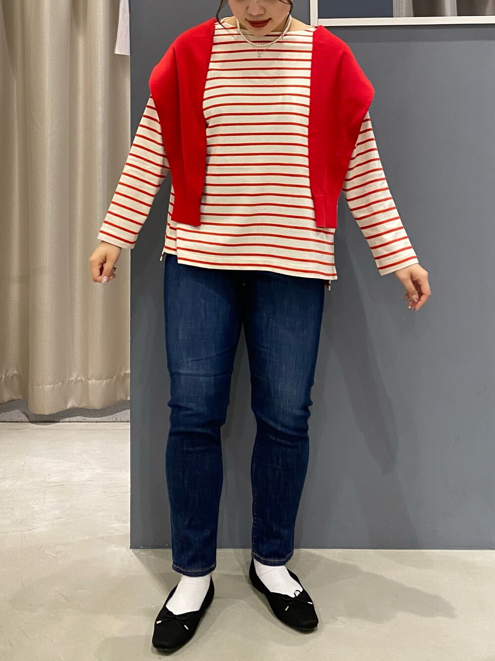 レッド系のTシャツ/カットソー、レッド系のカーディガン/ボレロ、ブルー系のデニムパンツを着用したレディースの春コーディネートの2枚目の写真