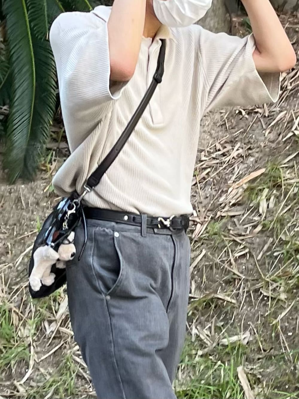 グレー系のデニムパンツ、ブラック系のブーツ、ベージュ系のポロシャツを着用したメンズの夏コーディネートの2枚目の写真