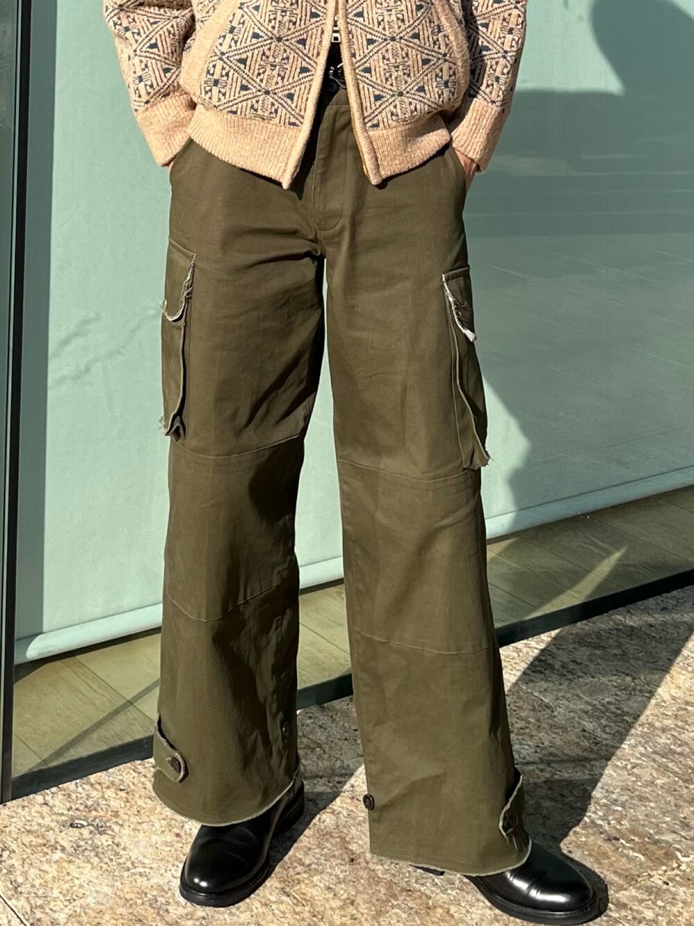 グリーン系のカーゴパンツ、ブラック系のブーツ、ベージュ系のニット/セーターを着用したメンズの冬コーディネートの3枚目の写真