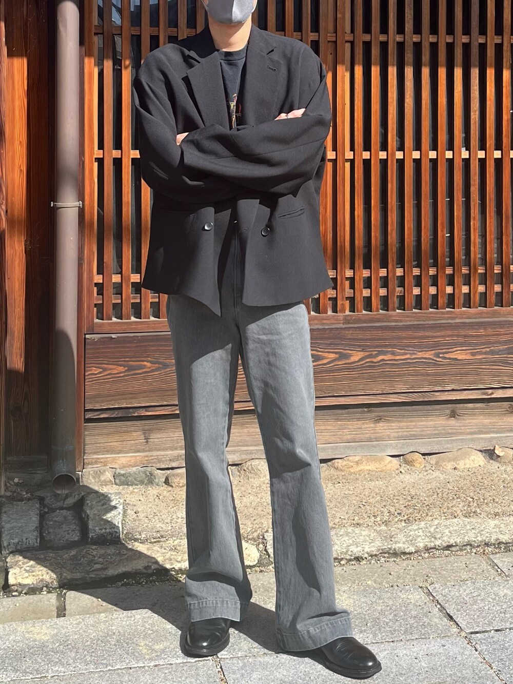 グレー系のデニムパンツ、ブラック系のテーラードジャケット、ブラック系のブーツを着用したメンズの春コーディネートの2枚目の写真