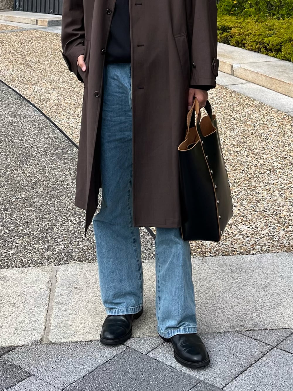 ブラック系のハンドバッグ、ブラック系のブーツ、ブルー系のデニムパンツを着用したメンズの冬コーディネートの5枚目の写真