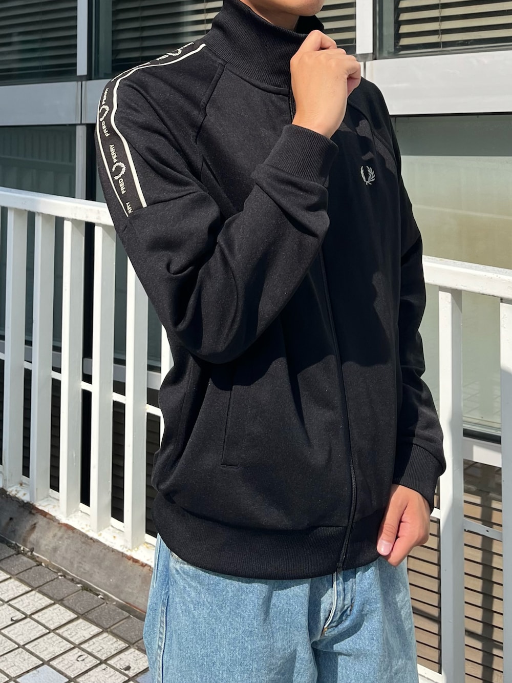 ブラック系のジャージ、ブラック系のハンドバッグ、ブルー系のデニムパンツを着用したメンズの秋コーディネートの3枚目の写真