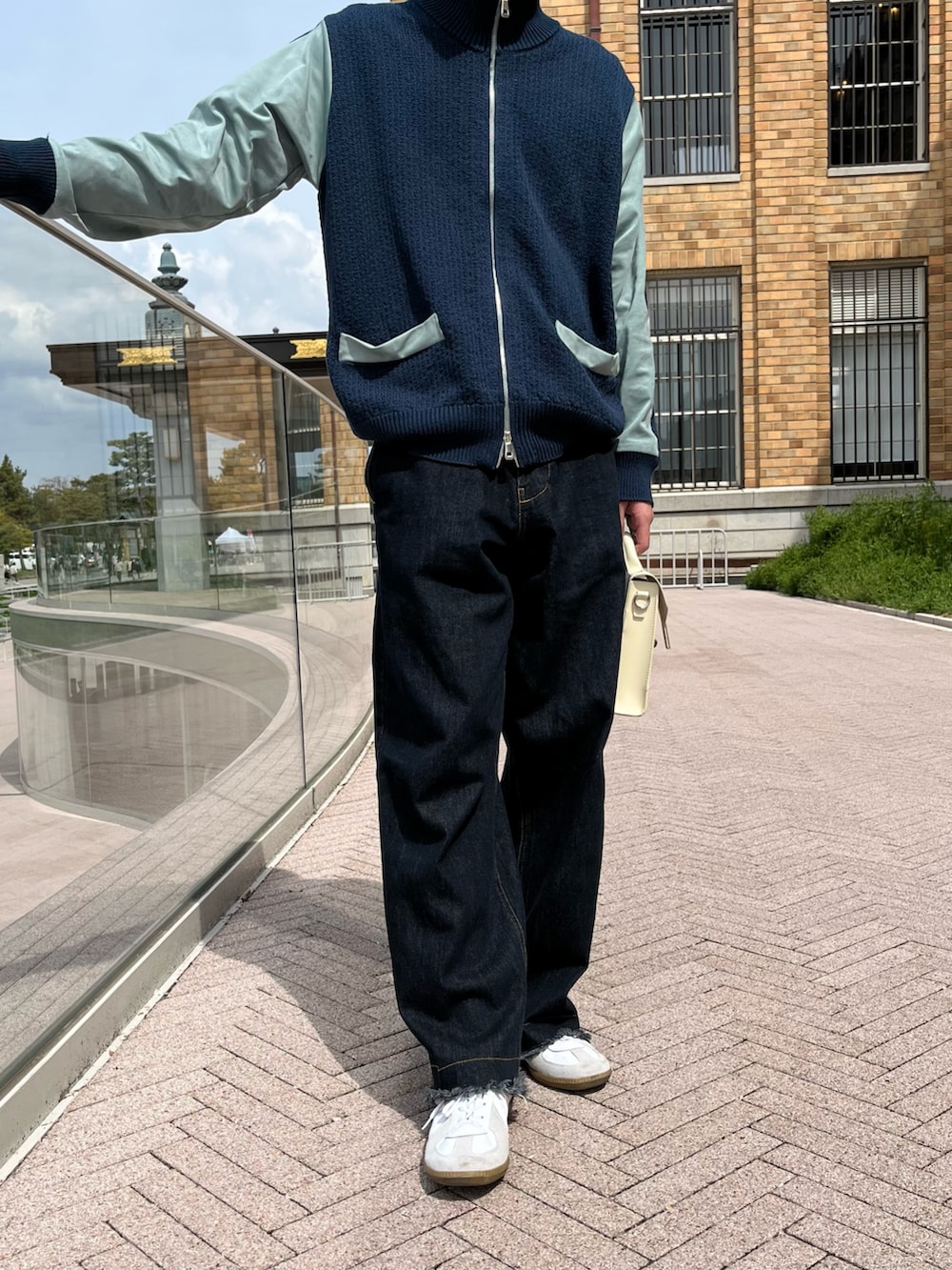 ブルー系のデニムパンツ、ホワイト系のショルダーバッグ、ホワイト系のスニーカーを着用したメンズの春コーディネートの3枚目の写真