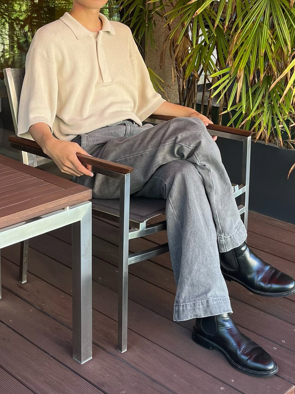 グレー系のデニムパンツ、ブラック系のブーツ、ベージュ系のポロシャツを着用したメンズの夏コーディネートの3枚目の写真