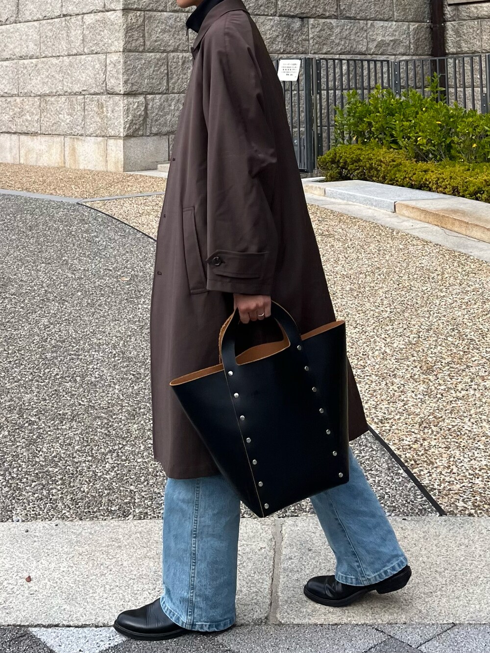 ブラック系のハンドバッグ、ブラック系のブーツ、ブルー系のデニムパンツを着用したメンズの冬コーディネートの3枚目の写真