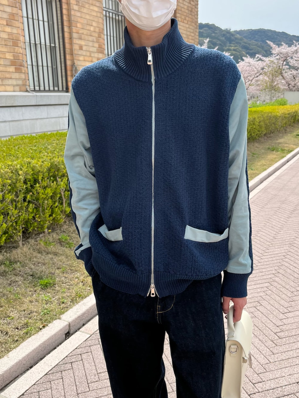 ブルー系のデニムパンツ、ホワイト系のショルダーバッグ、ホワイト系のスニーカーを着用したメンズの春コーディネートの4枚目の写真