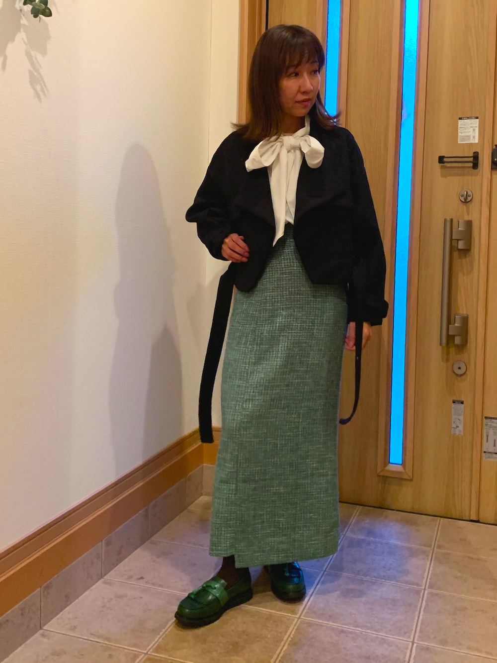 ブラック系のブルゾン、ホワイト系のシャツ/ブラウス、グリーン系のスカートを着用したレディースの秋コーディネートの2枚目の写真