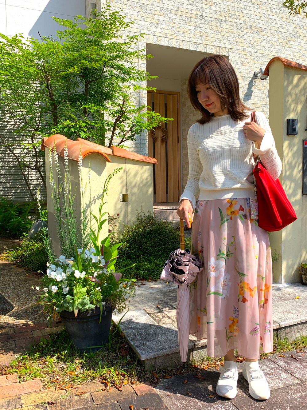 ホワイト系のスリッポン、オレンジ系のスカート、ホワイト系のニット/セーターを着用したレディースの春コーディネートの2枚目の写真