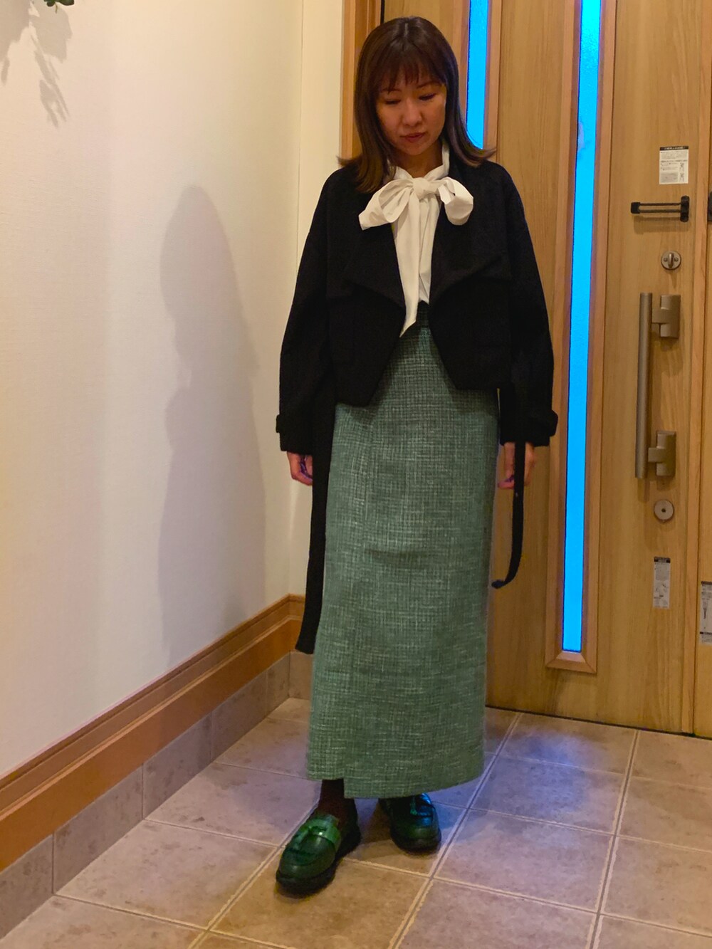 ブラック系のブルゾン、ホワイト系のシャツ/ブラウス、グリーン系のスカートを着用したレディースの秋コーディネートの3枚目の写真