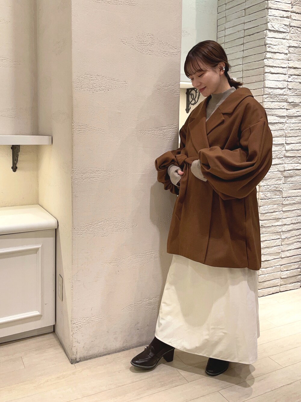 イエロー系のその他アウター、ベージュ系のニット/セーター、ホワイト系のスカートを着用したレディースの冬コーディネートの2枚目の写真